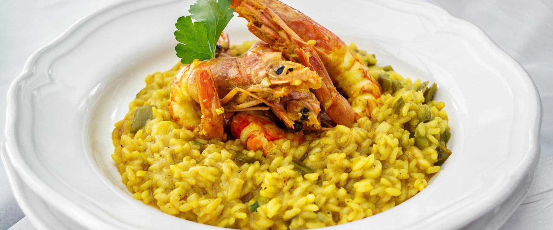 Risotto cremoso con gamberi, profumo di mare e zafferano, su piatto elegante.
