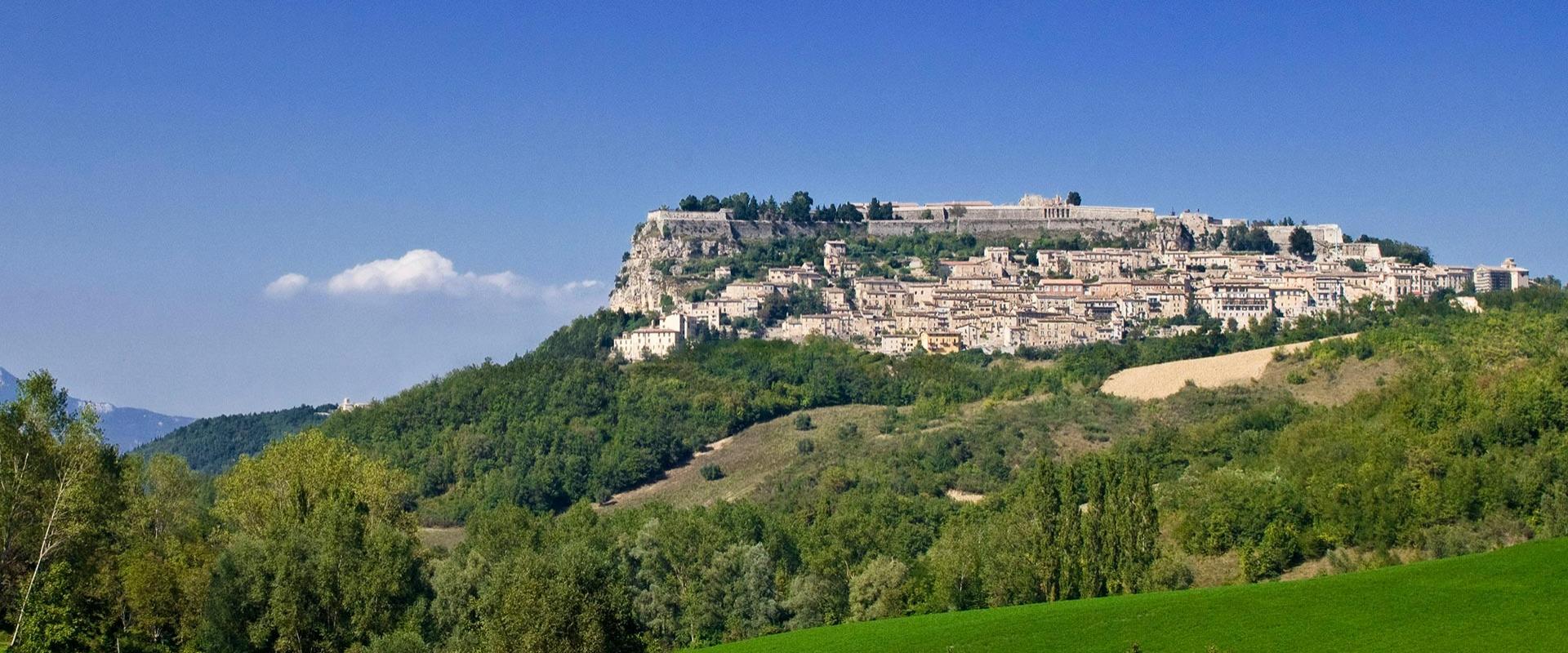Città antica su collina verde, sotto un cielo limpido e sereno.
