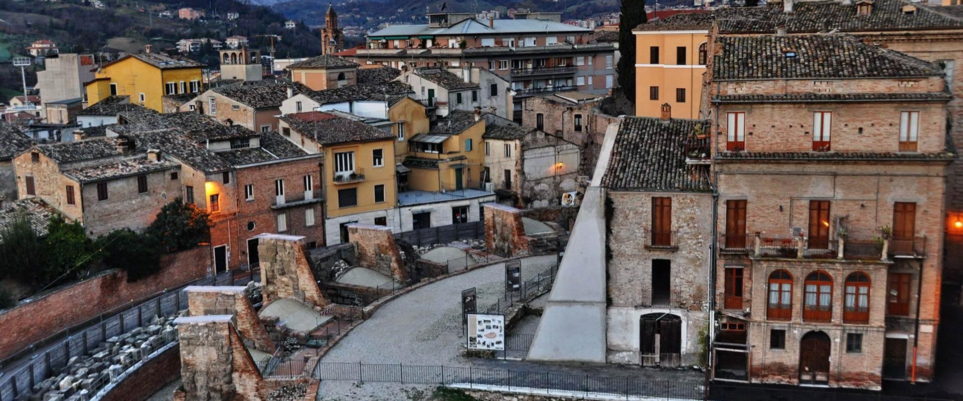 Antico borgo italiano al tramonto, tetti di pietra, mura storiche, atmosfera calda e accogliente.