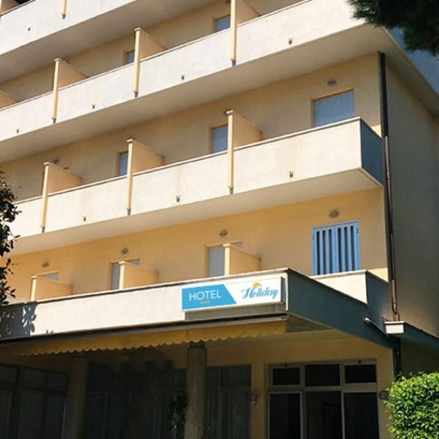 Facciata di hotel soleggiato con balconi accoglienti, invitante rifugio per relax e vacanza.