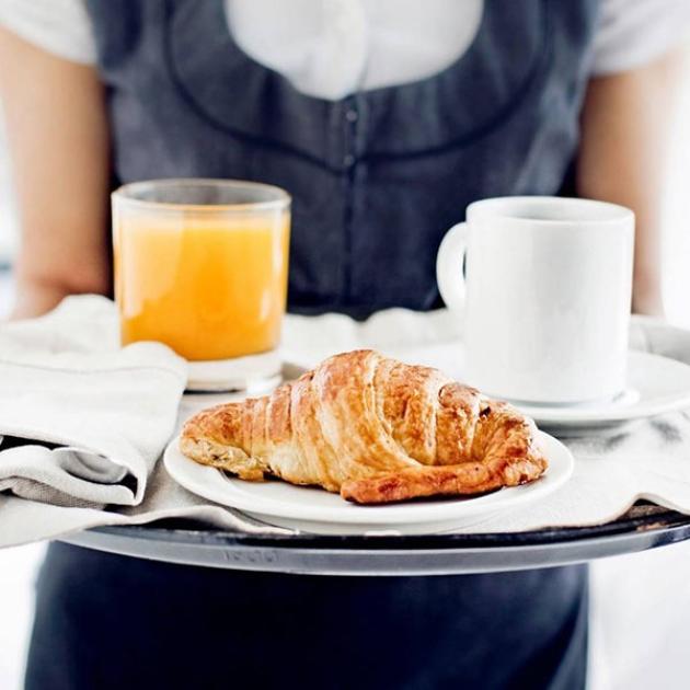 Colazione elegante: croissant, succo d'arancia e caffè, serviti con cura su un vassoio.