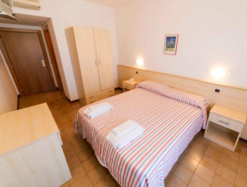 Camera semplice, accogliente, con letto matrimoniale e arredi chiari, atmosfera rilassante.